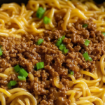 Delicious ground beef and noodles dish topped with green onions, served in a savory sauce for a comforting and flavorful meal.